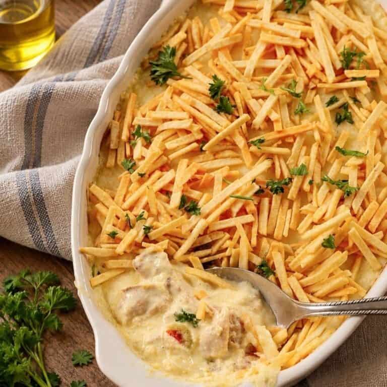 Creamy shredded chicken casserole topped with crispy shoestring potatoes and fresh parsley.