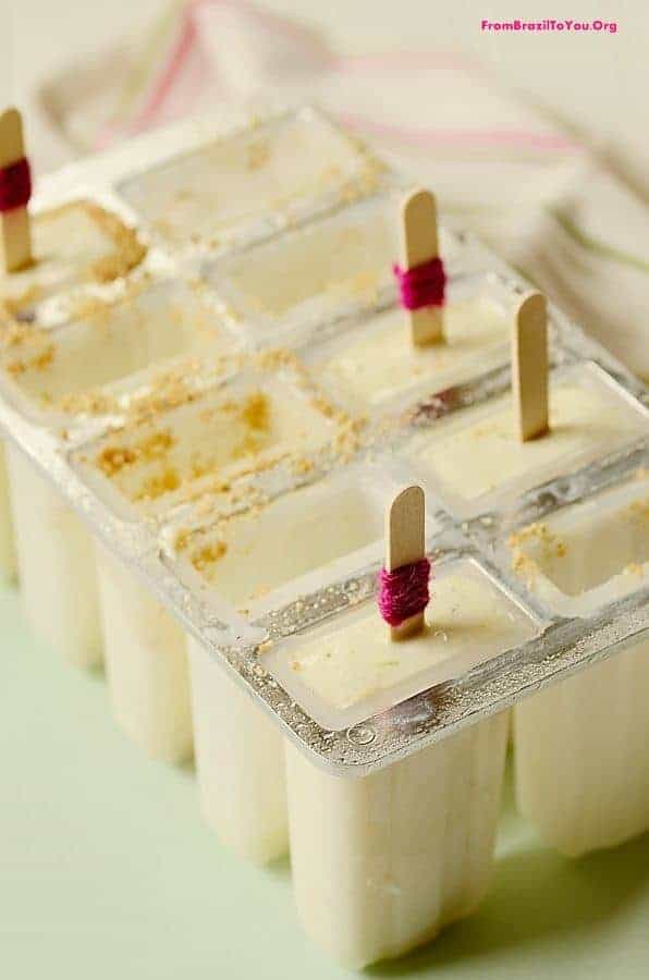 A filled popsicle tray with upright popsicle sticks inserted