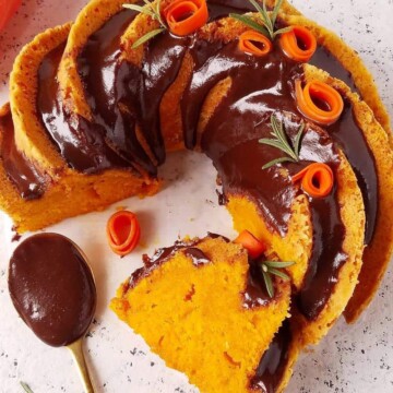 bolo de cenoura fofinho parcialmente fatiado com uma colher de cobertua de chocolate