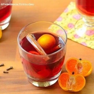 um copo de quentão de vinho com uma laranja partida ao meio do lado
