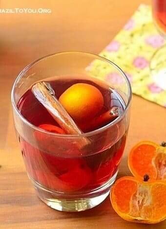 um copo de quentão de vinho com uma laranja partida ao meio do lado