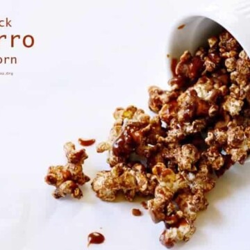 A cup pouring out cinnamon and sugar covered popcorn
