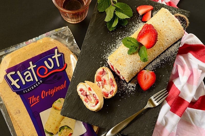 Sliced strawberry roll on a black board