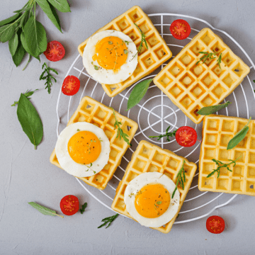 uma gradinha com waffle pão de queijo, ovos, tomates e ervas