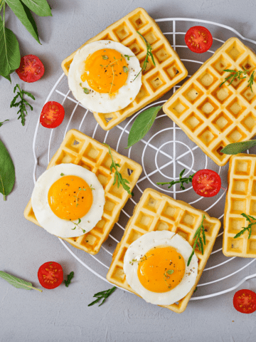 uma gradinha com waffle pão de queijo, ovos, tomates e ervas