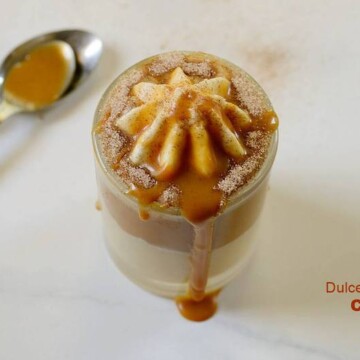 dulce de leche dessert in a glass cup with a spoon beside it