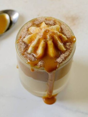 dulce de leche dessert in a glass cup with a spoon beside it