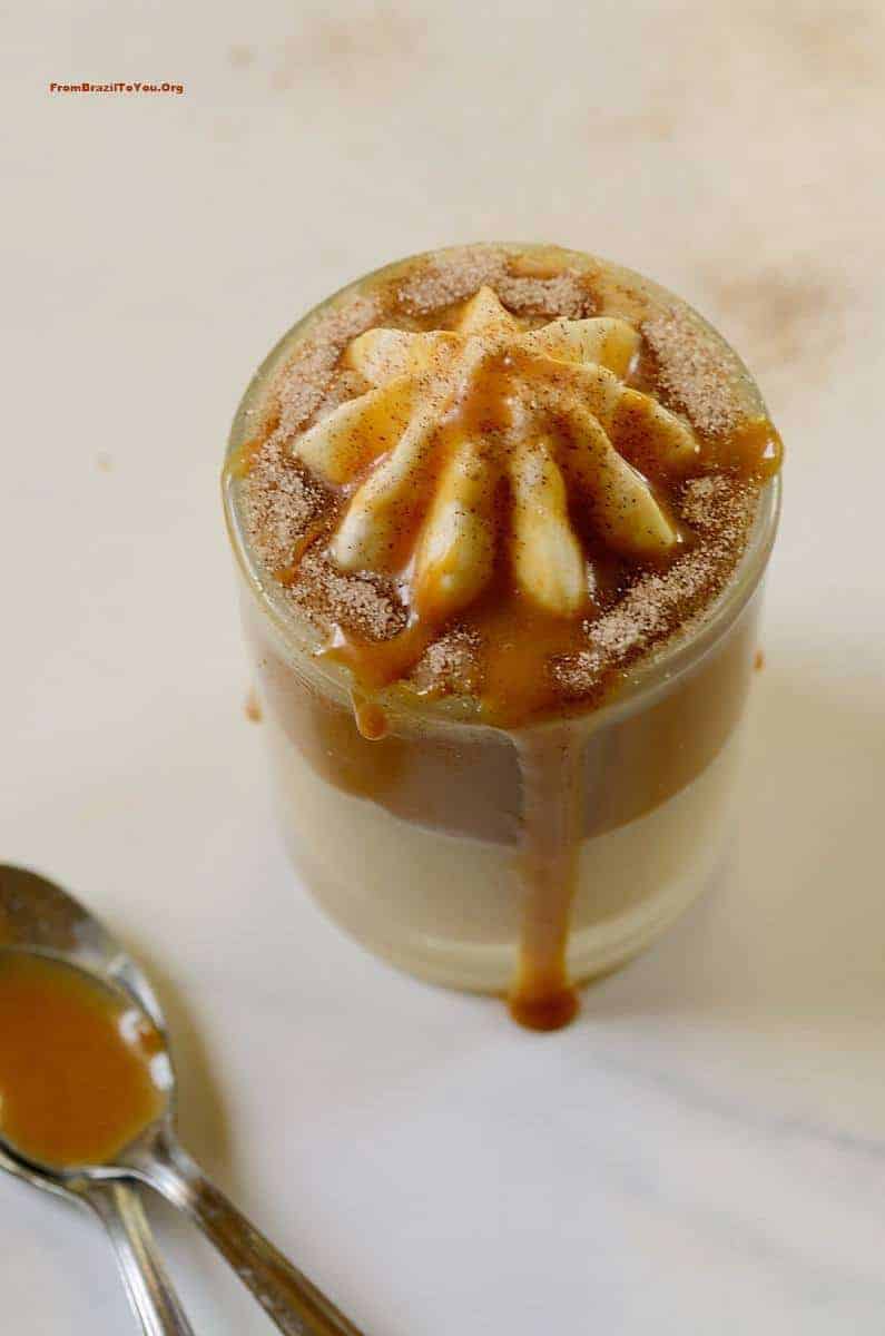 A cup with trifle dessert drizzled with caramel sauce