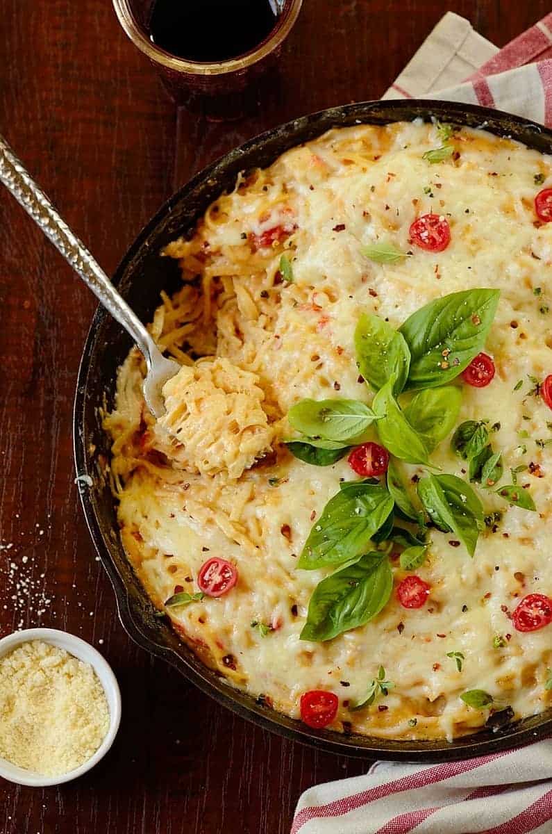 a skillet of chicken bacon pasta bake with garnishes around to serve as one of those easy chicken recipes for dinner