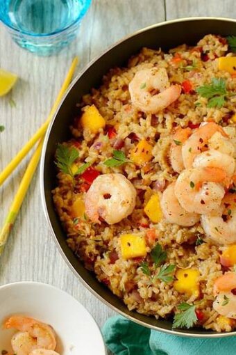 pan of coconut fried rice with shrimp on a table with chopsticks