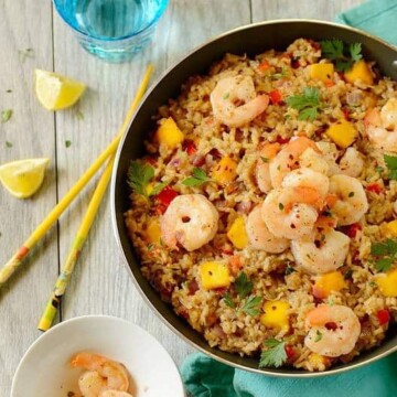 pan of coconut fried rice with shrimp on a table with chopsticks