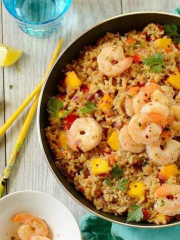 pan of coconut fried rice with shrimp on a table with chopsticks