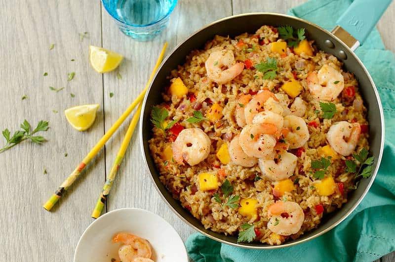 pan of coconut fried rice with shrimp on a table with chopsticks