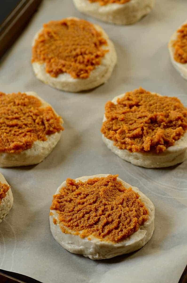 topping biscuits with pumpkin puree onto a baking sheet