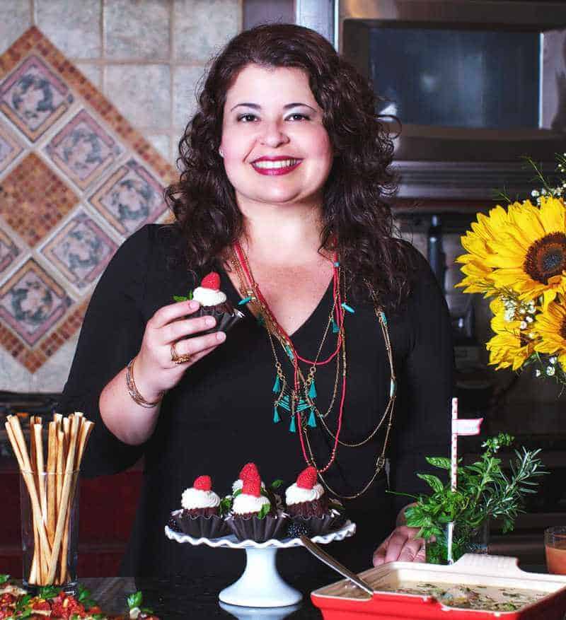 Blog author in the kitchen holding a cupcake. 