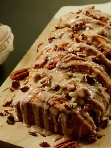 A slice of pumpkin bread on top of a wooden cutting board