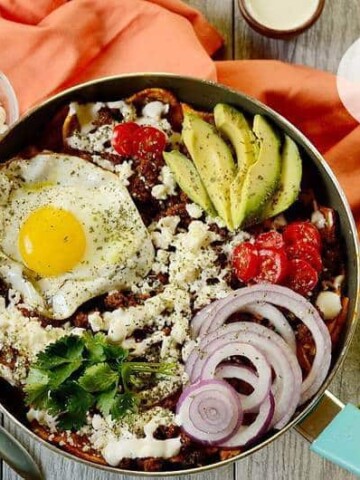 A bowl of breakfast chilaquiles on a table.