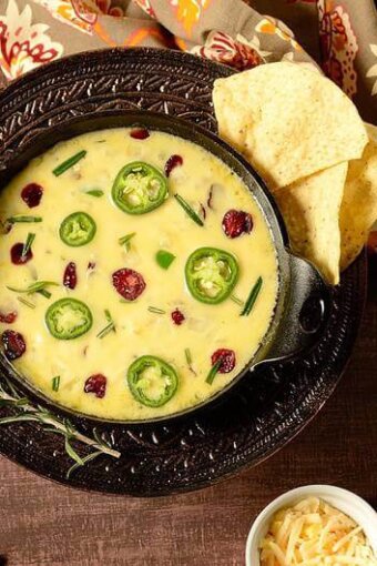 A bowl of queso fundido with some chips on the side.