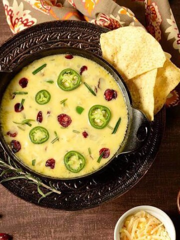 A bowl of queso fundido with some chips on the side.