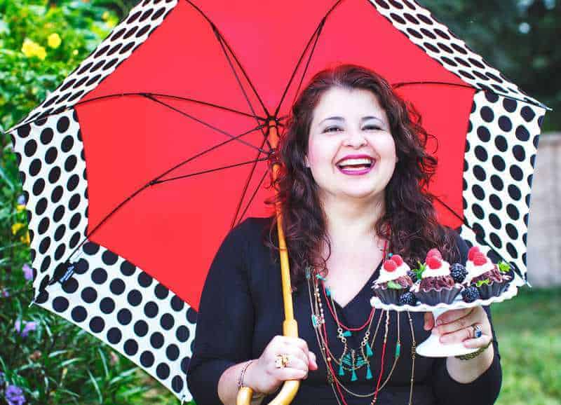 Denise Browning holding a colorful umbrella and a tray of cupcakes