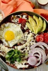 close up of a pan with breakfast chilaquiles and many toppings.