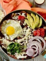 close up of a pan with breakfast chilaquiles and many toppings.