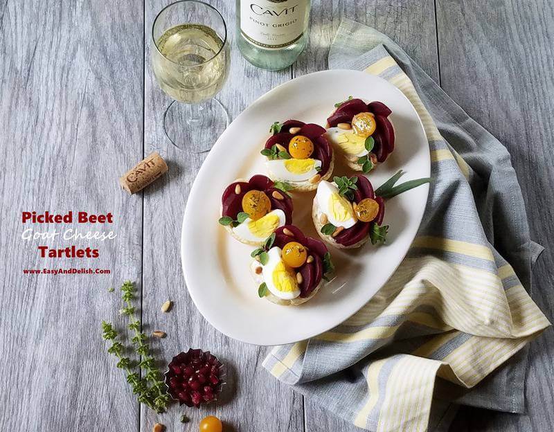 A plate with puffy pastry tartlets plus wine and garnishes surrounding the plate