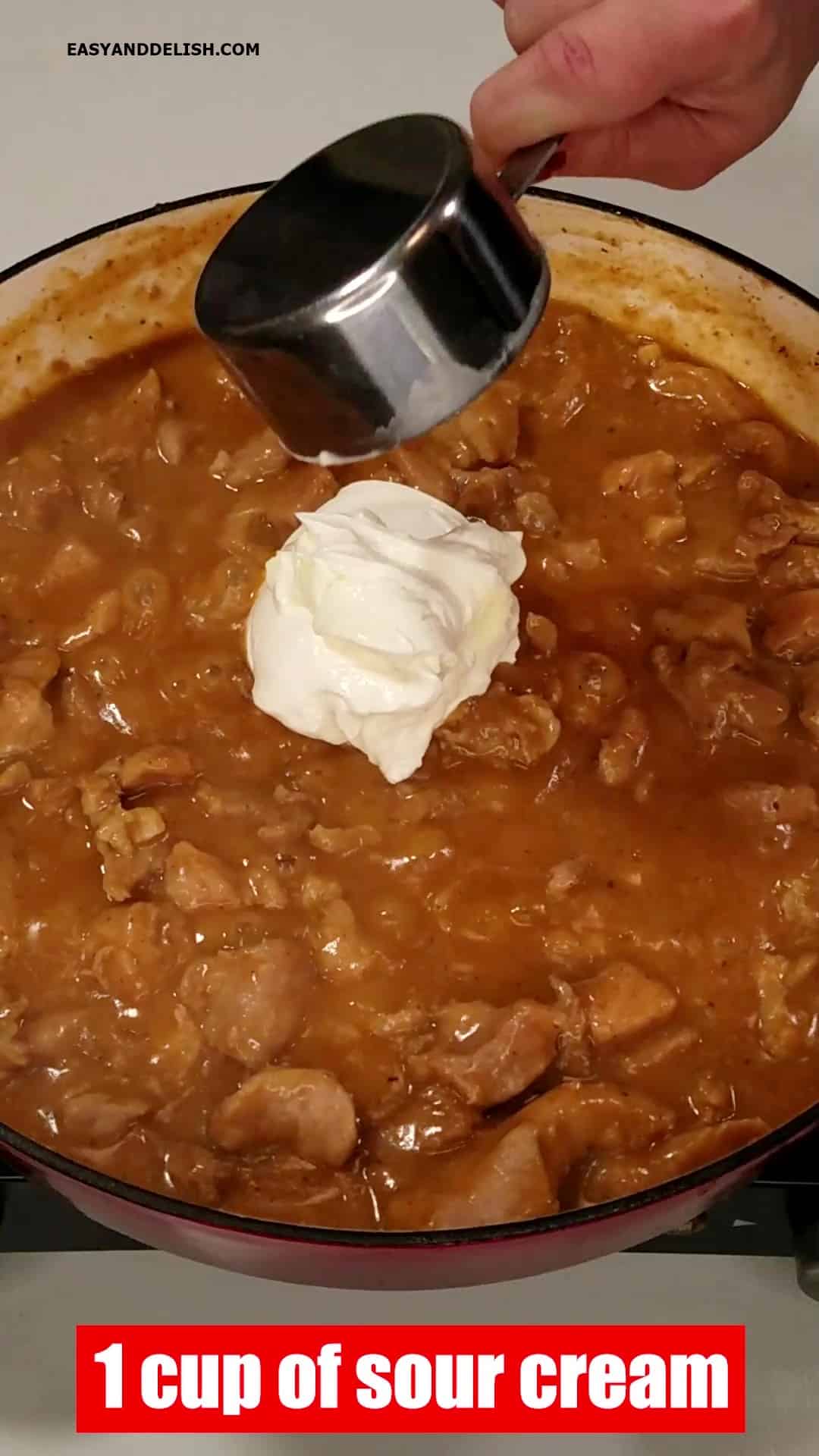 Adding sour cream to the cooked pork stroganoff.