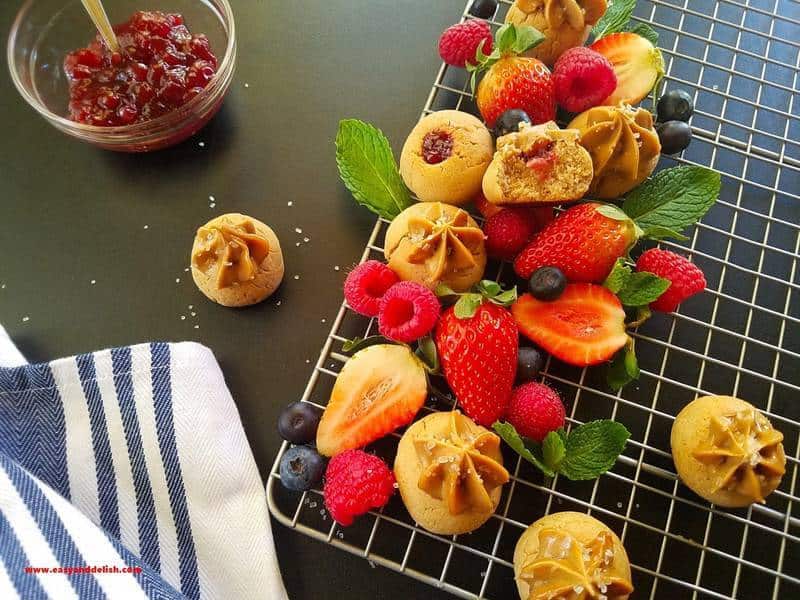 A rack of peanut butter and jelly cookies and berries