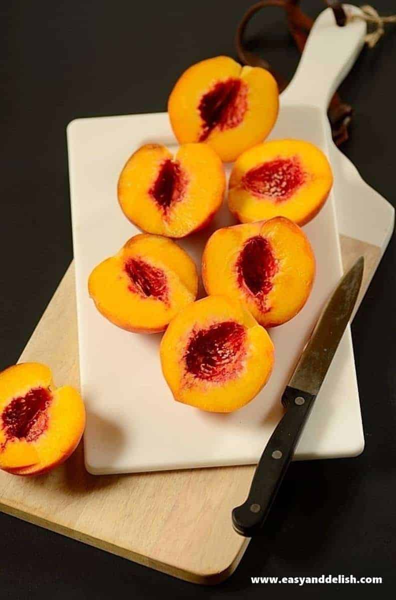 peach halves on a cutting board with a kinfe