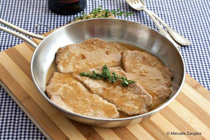 Steaks with sauce in a skillet.