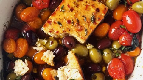 a baking dish with baked feta, roasted Greek veggies, and crostini