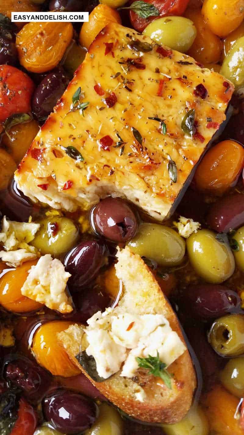 close up of a block of baked feta partially sliced and served on crostini