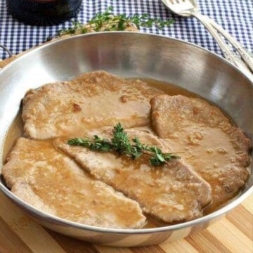 A skillet with veal marsala garnished with fresh herbs on top.