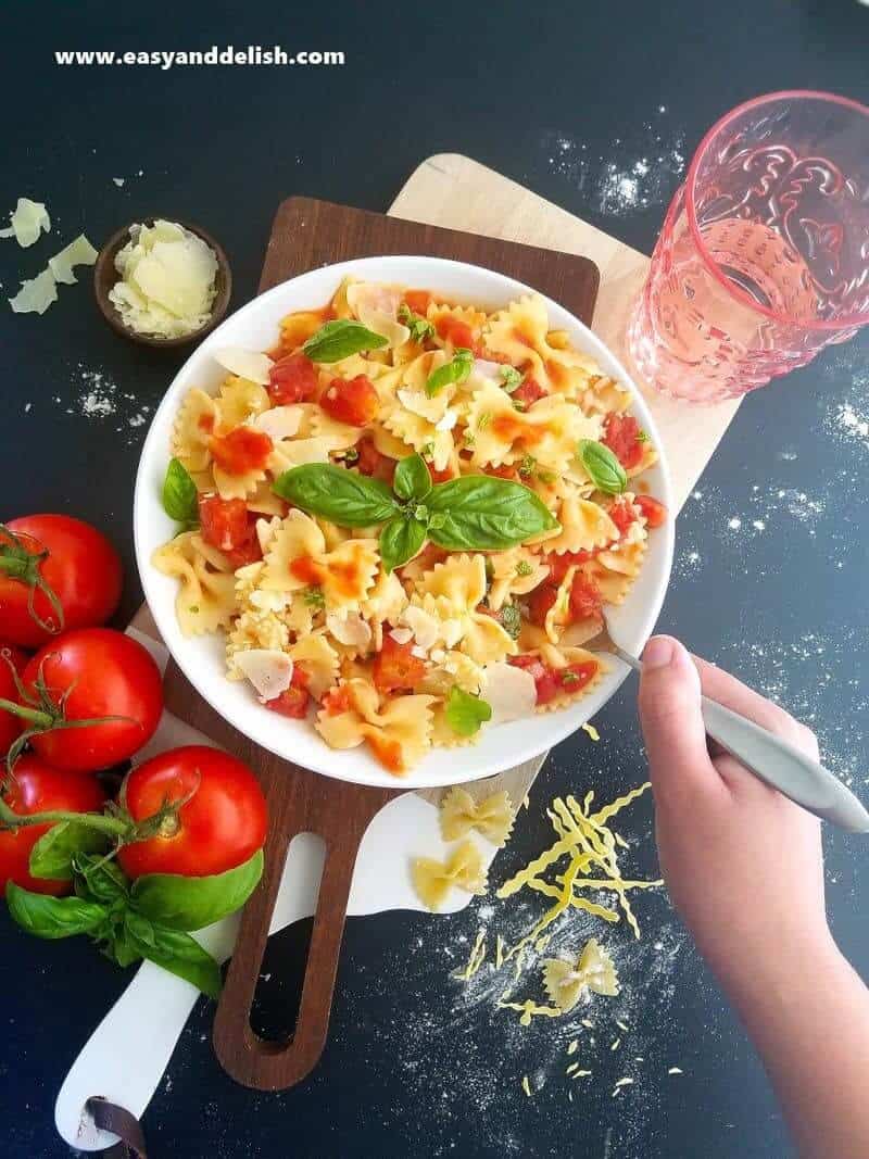 A person holding a fork with a plate of pasta