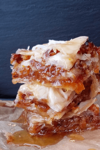 a pile of nut-free vegan baklava on aprchment paper drizzled with syrup.