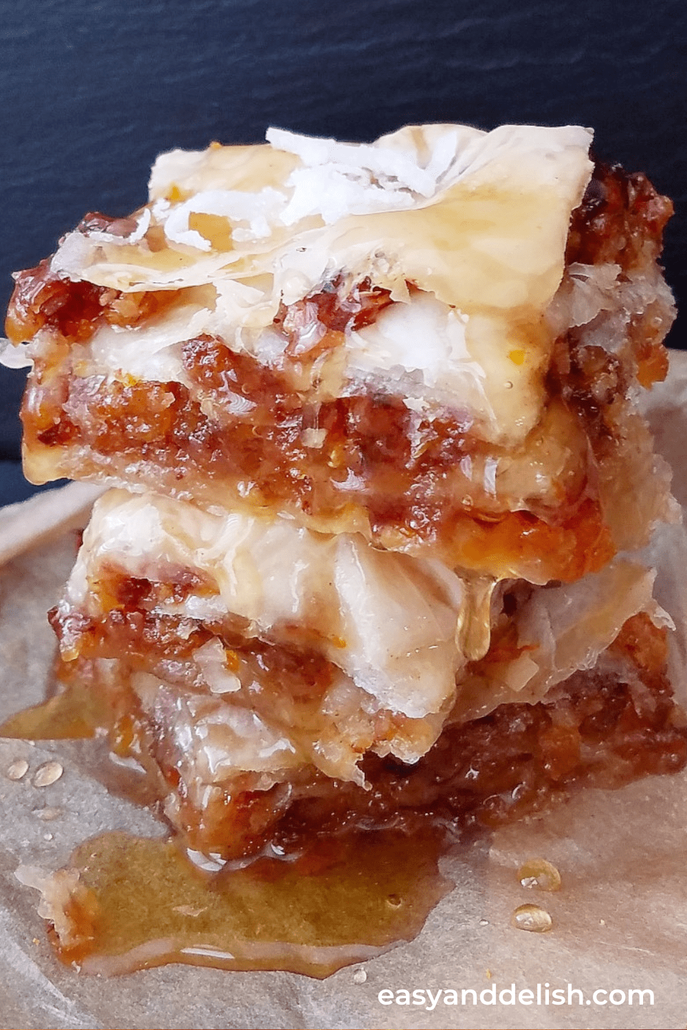 a stack of vegan baklava squares over parchment paper