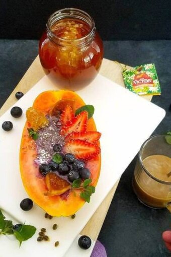 papaya boats with a cup of coffee and a jar of honey