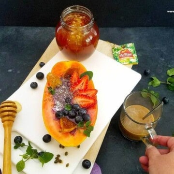 papaya boats with a cup of coffee and a jar of honey