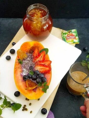 papaya boats with a cup of coffee and a jar of honey