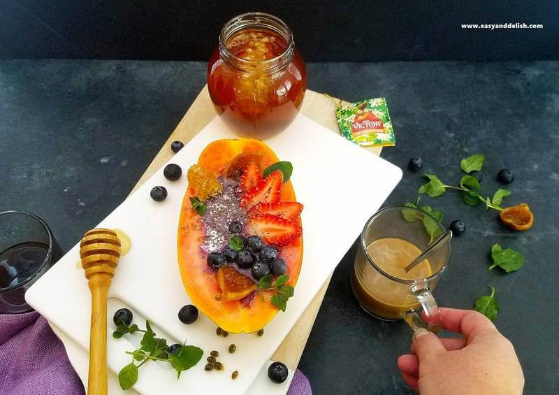 papaya boats with a cup of coffee and a jar of honey