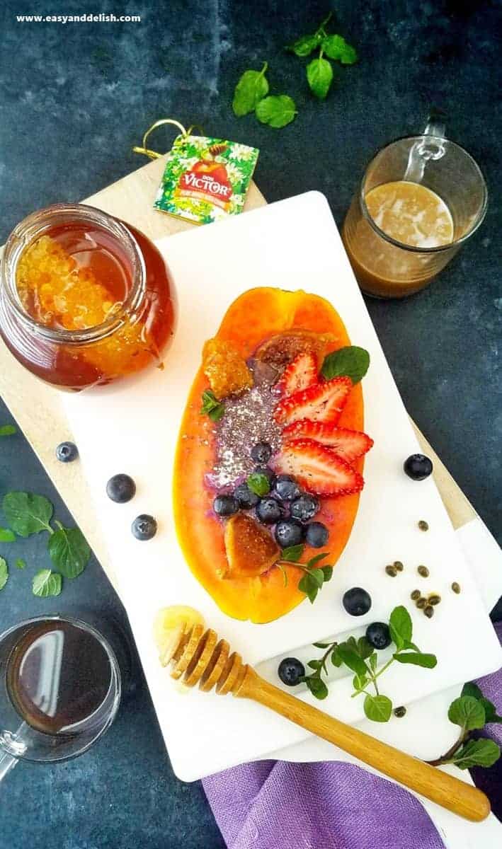 A plate with a papaya bowl and a jar of honey