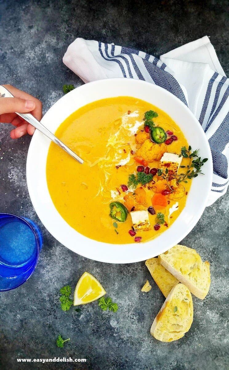 a bowl of cauliflower soup with garnishes on the side