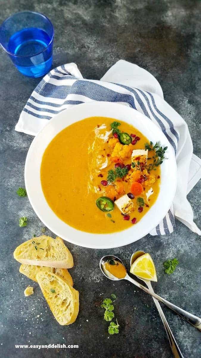 a bowl of cauliflower curry soup with bread on the side