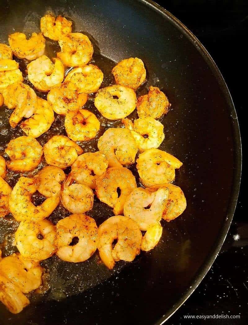Close up image of spicvy shrimp being cooked in a pan, showing one of the cooking steps.