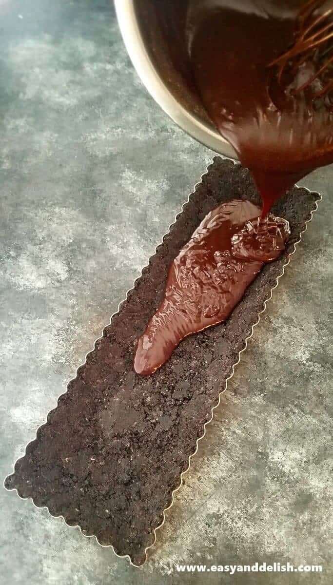 Image of nutella filling being poured into the baking pan over the Oreo crust