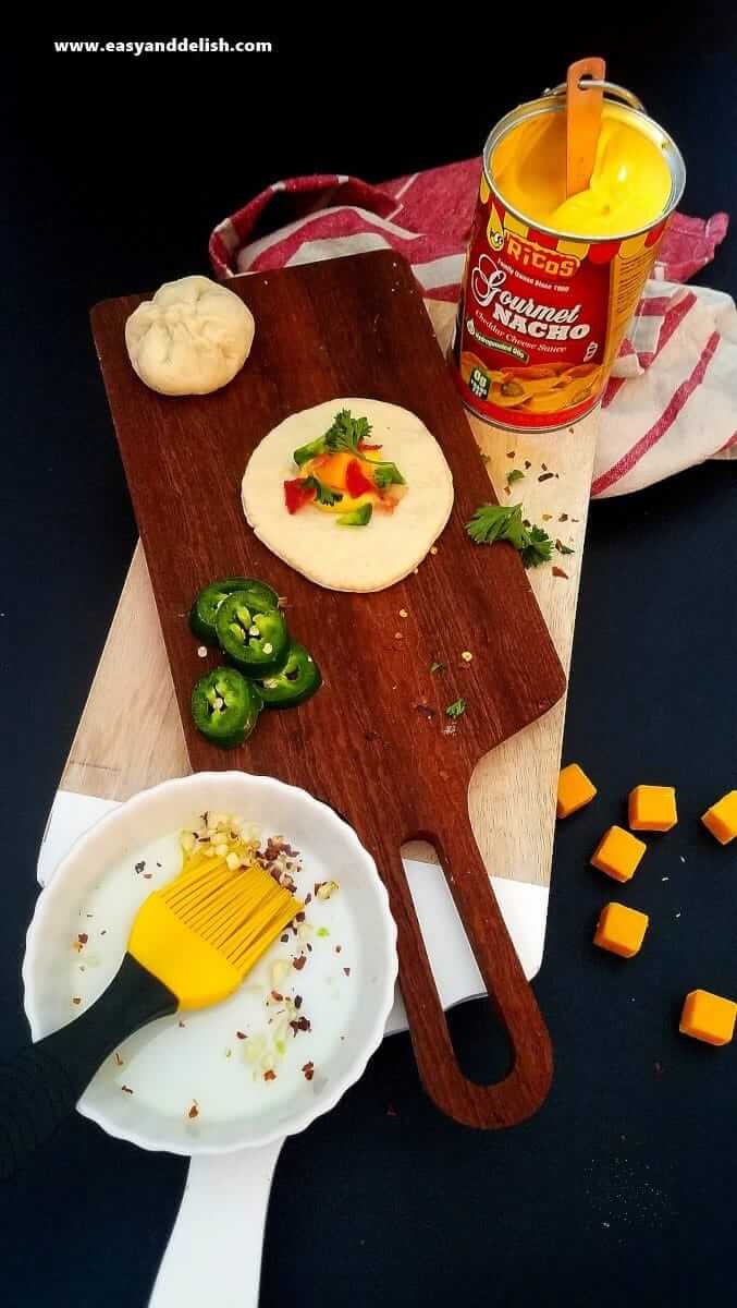 Image displaying filling of Nacho Pizza Bombs spooned in the center of dough.