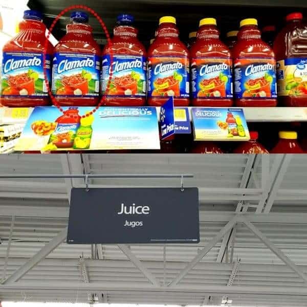 Walmart shelf with bottles of Clamato tomato juice and a juice aisle sign.