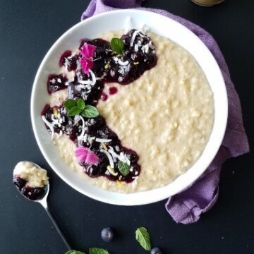 A bowl of coconut oatmeal pudding topped with blueberry sauce
