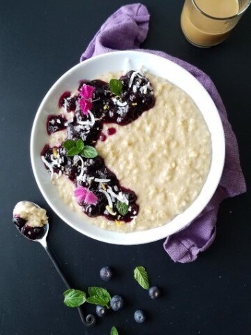 A bowl of coconut oatmeal pudding topped with blueberry sauce